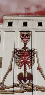 Skeleton mural on building under red sky.