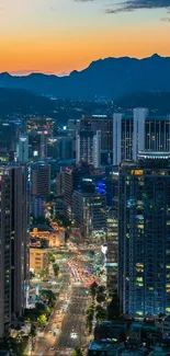 Cityscape view at dusk with sunset and illuminated skyscrapers.