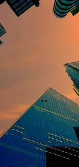 Urban skyline at sunset with tall skyscrapers and orange sky.