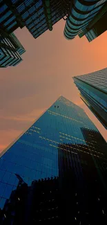 Looking up at modern skyscrapers during orange sunset sky.