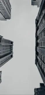 Upward view of urban skyscrapers with a gray sky backdrop.