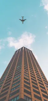 A striking skyscraper reaches up as an airplane flies above in a clear blue sky.