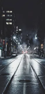 Dimly lit urban street at night with city lights and wet pavement.