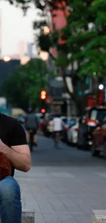 Man holding dog on an urban street with city lights and cars in the background.