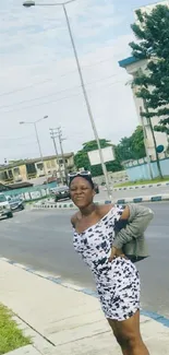 Woman in a patterned dress on an urban street with greenery.