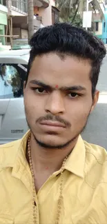 Urban street portrait with yellow shirt and city background.