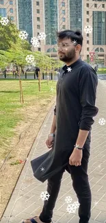 Man in black outfit on urban street with modern buildings.