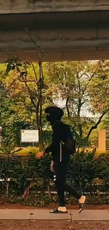 Person walking under a city bridge surrounded by greenery.