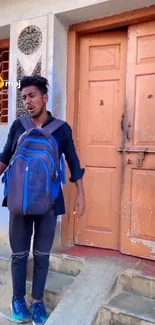 Young man with backpack at orange door.