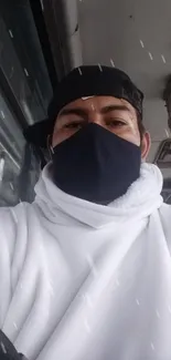 Portrait of a masked person on a bus, wearing a white hoodie.