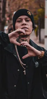 A person in urban streetwear making a heart shape with their hands.