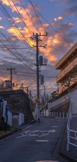 Urban street at sunset with glowing clouds and power lines.