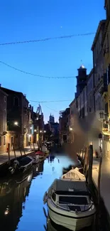 Venetian canal at dusk with boats and reflections in twilight.