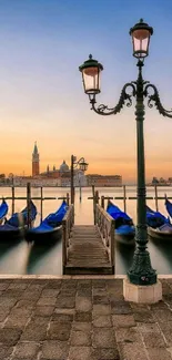 Venice gondolas at sunset with street lamp and orange sky.