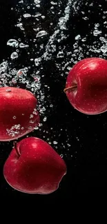 Vibrant red apples with bubbles underwater.