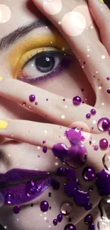 Face with vibrant yellow and purple makeup, dotted with colorful liquid droplets.