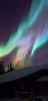 Colorful Aurora Borealis above snowy cabin.