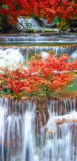 Cascading waterfall with vibrant red autumn leaves and lush greenery.