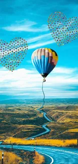 Colorful hot air balloon over winding road under blue sky.