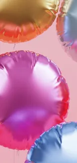 Colorful metallic balloons on pink background.