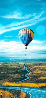 Vibrant hot air balloon over winding road under blue sky.
