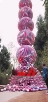 Colorful balloon tower against a forested backdrop.