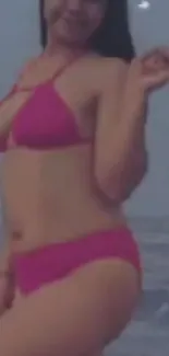 Woman in vibrant pink bikini on a beach.