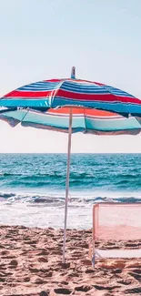 Vibrant beach with colorful umbrella and chair by the ocean.