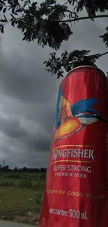 Vibrant red beer can against a dramatic outdoor background.