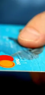 Close-up of a hand holding a blue credit card.