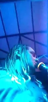 Performer singing under blue neon lights at a concert.