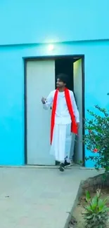 Man in traditional attire exiting a vibrant turquoise building.