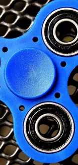 Blue fidget spinner on a textured black background, stylish wallpaper.