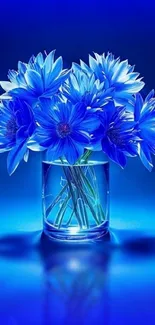 Vibrant blue flowers in a glass vase against a vivid blue background.