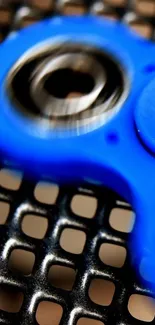 Vibrant blue fidget spinner on metallic grid background.