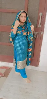 Woman in vibrant blue traditional outfit with patterns.