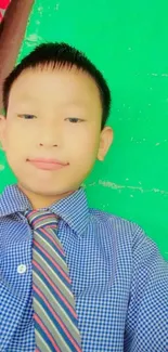 Boy in checkered shirt with green background.