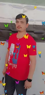 Man with butterflies in a red shirt on a vibrant background.