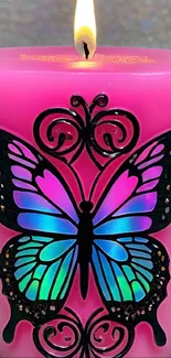 A vibrant pink candle with a colorful butterfly design, flame lit.