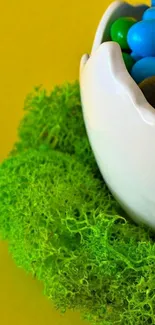 Egg-shaped bowl of colorful candies on a vibrant moss and yellow background.