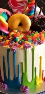 A colorful cake topped with candies and doughnuts.