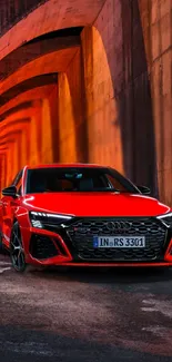 Red car in modern tunnel under vibrant lighting.