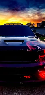 Sleek black car with red lights against a vibrant sunset backdrop.