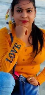 Woman in mustard top at the beach, posing with a scenic ocean backdrop.