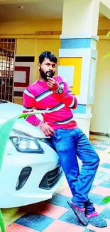 Man in colorful attire leaning on car in vibrant urban setting.