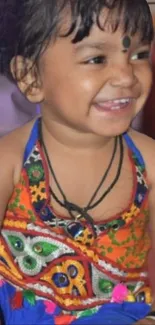 Smiling child in colorful traditional dress.