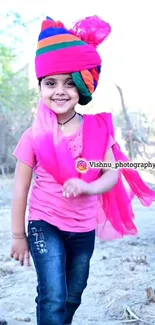 Smiling child in colorful traditional attire with pink dominant shades.