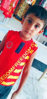 A vibrant portrait of a young boy wearing a red shirt against a lively background.