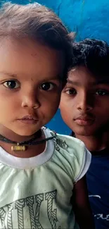 Portrait of two children with blue backdrop.