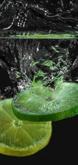 Lime and lemon slices splash in water on a dark background.